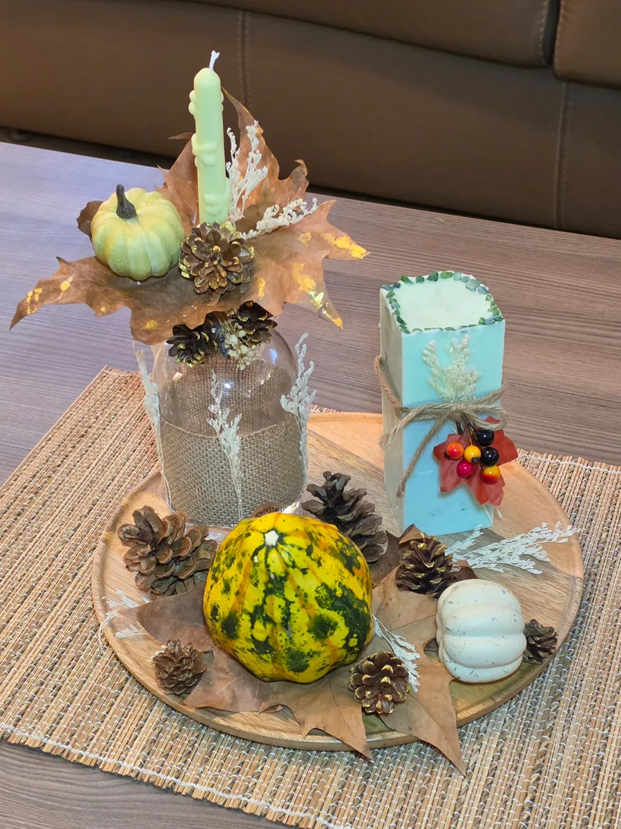 Composition de saison avec bougies, courges et pommes de pin